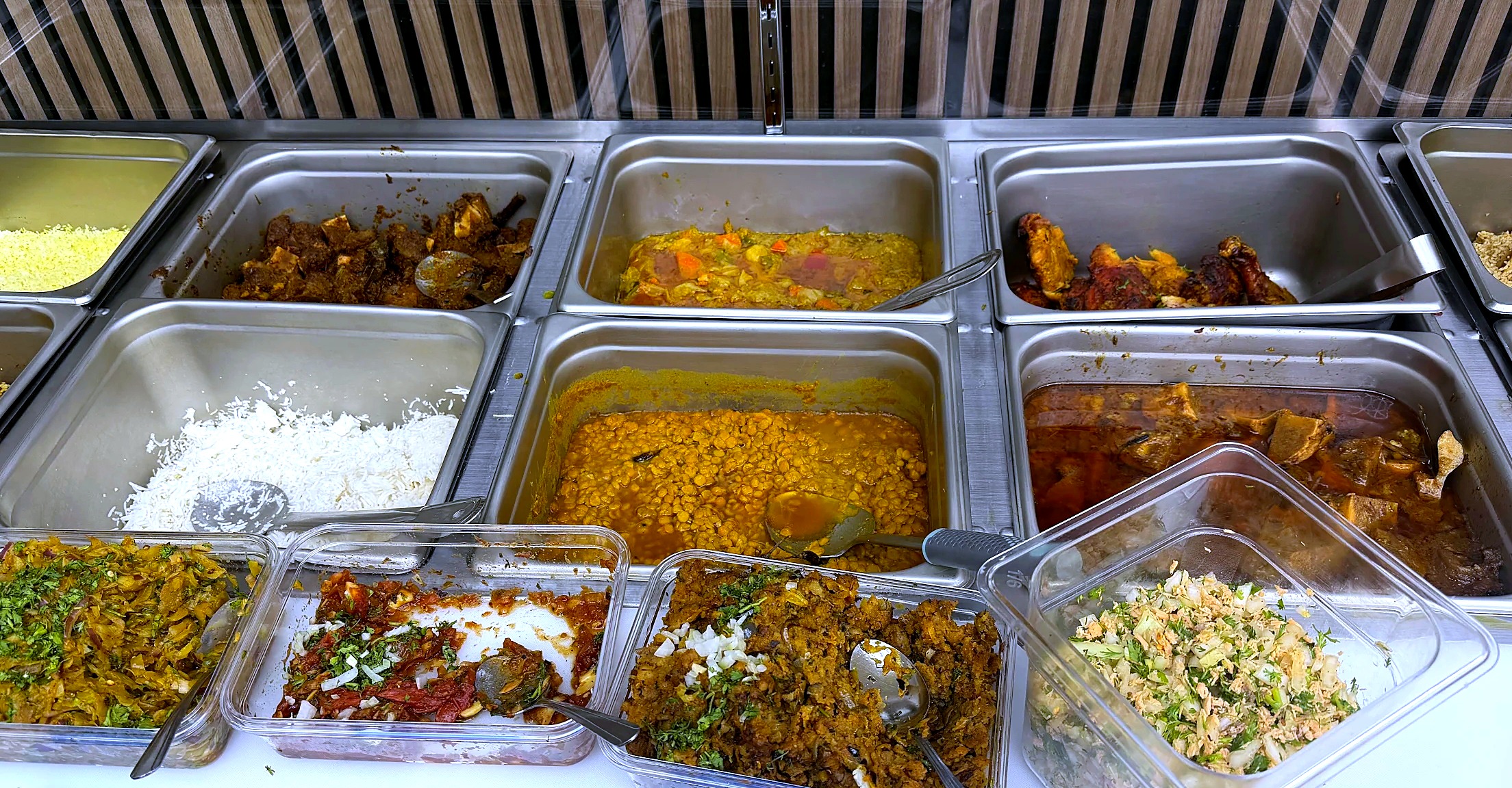 Daily buffet line at Shukriya — yellow rice, lamb, lentils, curries and salads